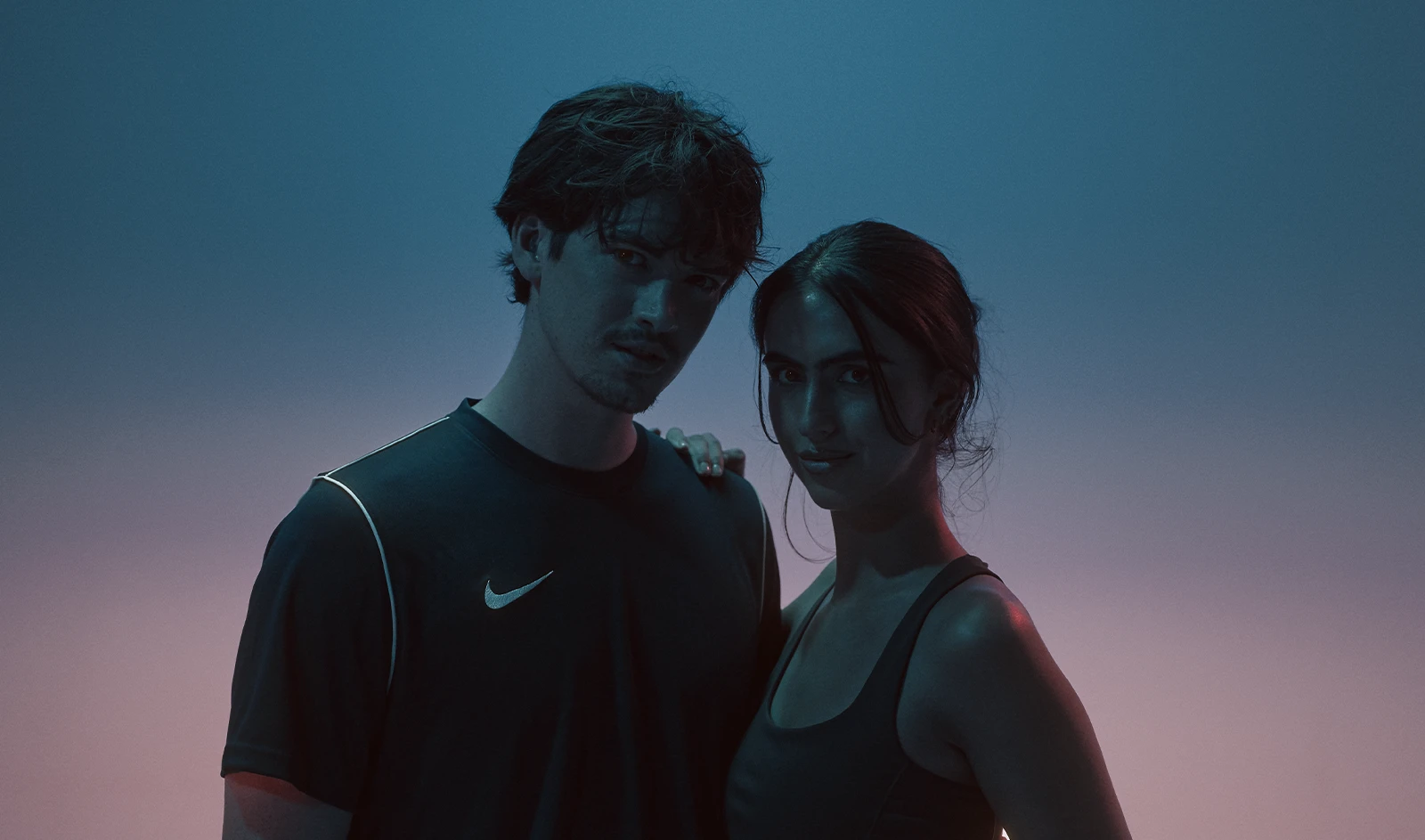 Man en vrouw naast elkaar in blauw licht na een training bij Coached